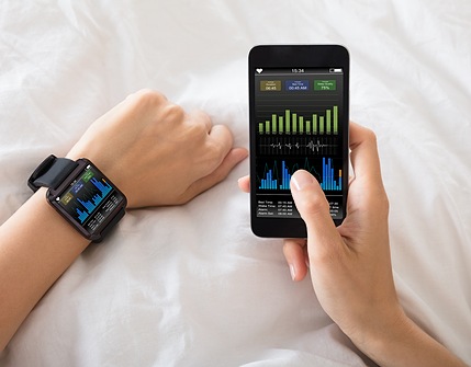 hand with smart watch next to a hand holding a smart phone